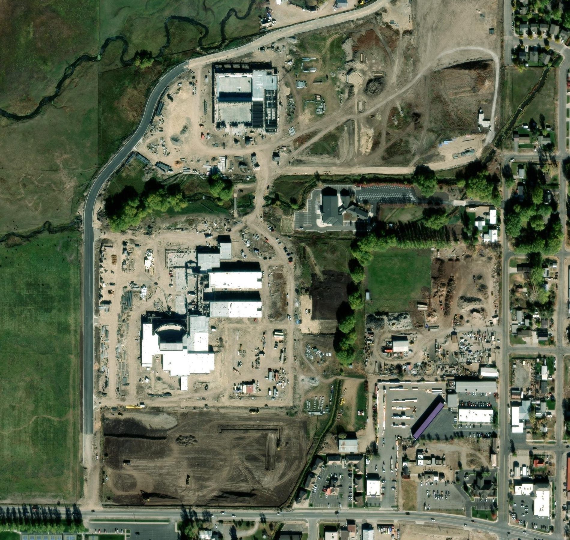 Satellite photo, October 2024: the school under construction, with the willows left standing along the creek
