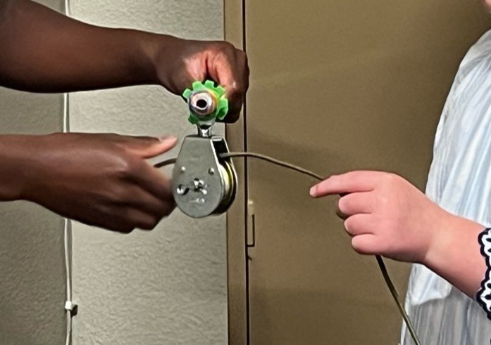 Hands working a pulley puzzle in the How to Land a Spaceship escape room
