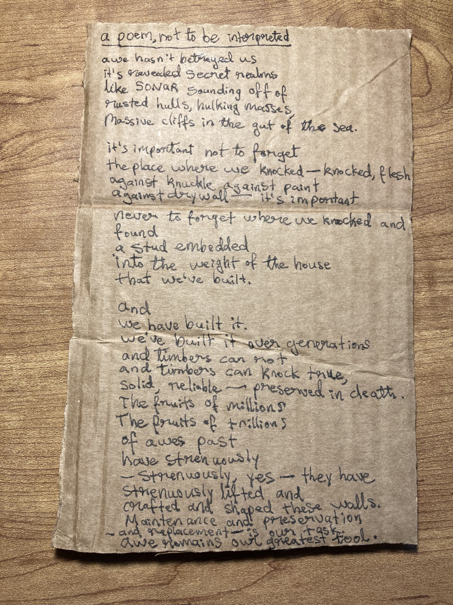 A handwritten poem on cardboard: “a poem, not to be interpreted”