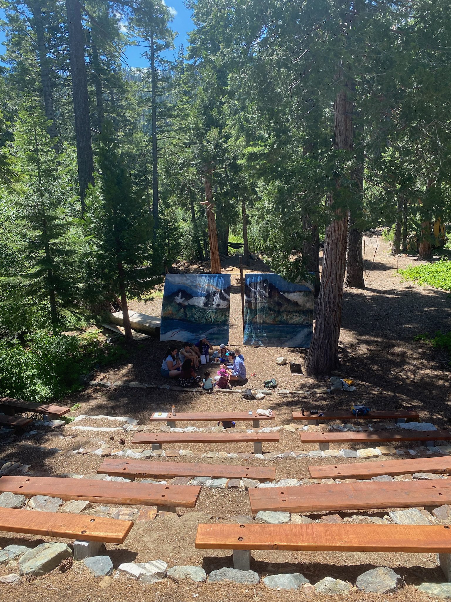 An outdoor amphitheater in the pines at Stanford Sierra Camp, a group gathered at the front